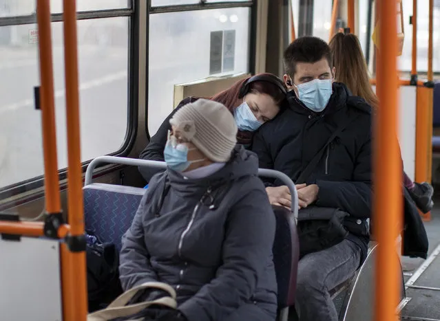 People wearing face masks to prevent the spread of coronavirus, travel by bus in Vilnius, Lithuania, Tuesday, November 10, 2020. The entire country has been put under a three-week nationwide lockdown from 7 November to 29 November, putting restrictions on social life and economic activities in order to stem the spread of the coronavirus. (Photo by Mindaugas Kulbis/AP Photo)