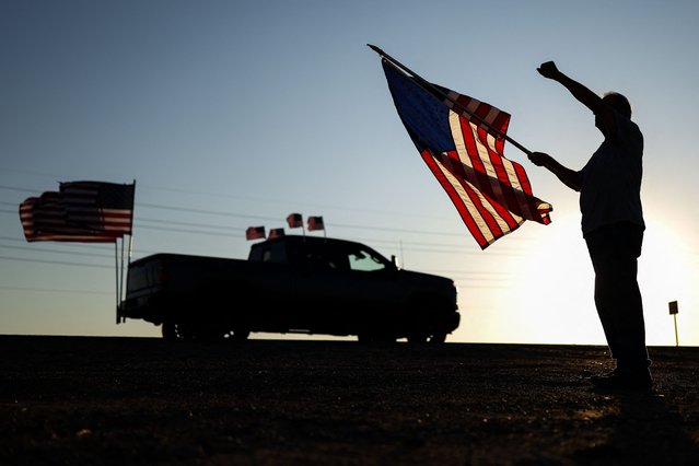 A man holding a US flag raises a fist as a rally in memory of right-wing activist Charlie Kirk drives past on September 13, 2025 in Surprise, Arizona. The 31-year-old Kirk was hit by a single bullet while addressing a large crowd at Utah Valley University in the town of Orem on September 10. (Photo by Charly Triballeau/AFP Photo)