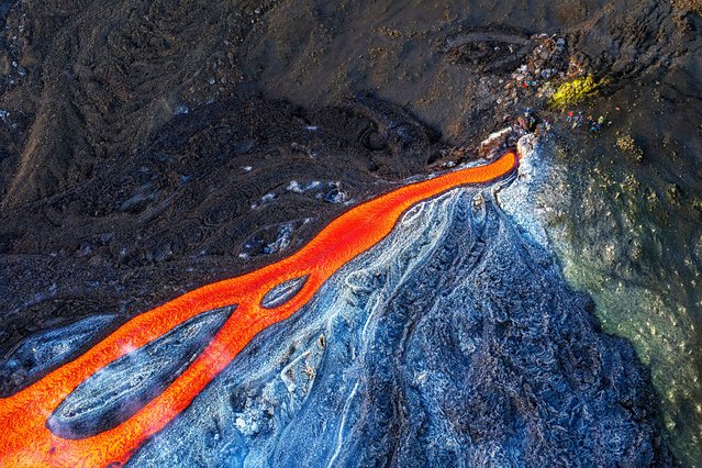 This aerial view shows people standing a flow of lava from the Mount Etna volcano (Torre del Filosofo – Etna Sud) on August 28, 2025. The Etna volcanic eruption started on August 10 and remain active the last weeks. (Photo by Giuseppe Distefano/AFP Photo)