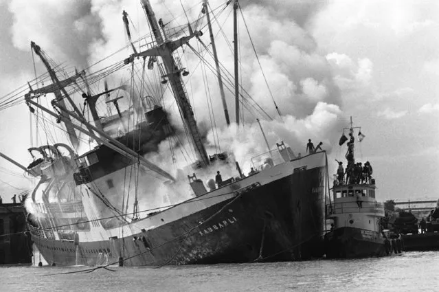 Philippine owned freighter Kabbarli burns at a dock in Phnom Penh after being struck by insurgent rocket fire en route to the Cambodian capital on Friday, August 3, 1974. Firemen failed to quench the blaze on the vessel making the hazardous Mekong River run and it sank from the weight of water poured on burning cargo. (Photo by AP Photo Moonface)