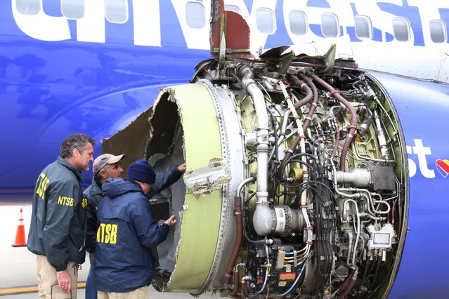 National Transportation Safety Board investigators examine damage to the engine of the Southwest Airlines plane that made an emergency landing at Philadelphia International Airport in Philadelphia on Tuesday, April 17, 2018. The Southwest Airlines jet blew the engine at 32,000 feet and got hit by shrapnel that smashed a window, setting off a desperate scramble by passengers to save a woman from getting sucked out. She later died, and seven others were injured. (Photo by NTSB via AP Photo)