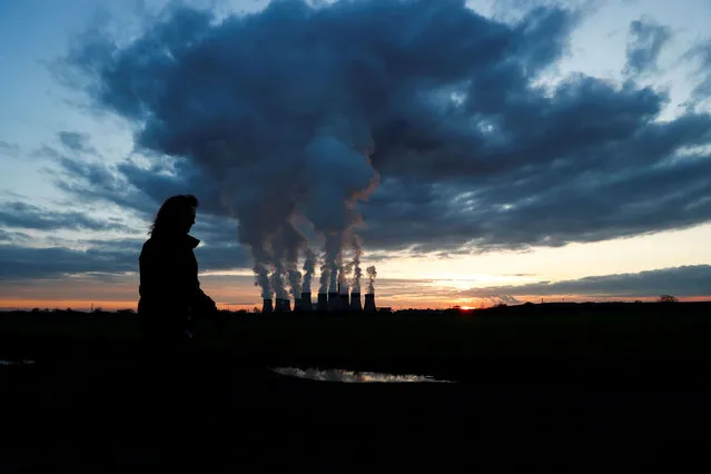A woman walks a dog past Drax power station during the sunset in Drax, North Yorkshire, Britain, November 27, 2020. (Photo by Lee Smith/Reuters)