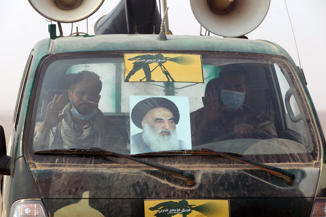 Iraqi pro-government forces ride on a vehicle adorned with an image of Iraqi Ayatollah Ali Husaini al-Sistani, in the al-Shura area, south of Mosul, on October 24, 2016, during an operation to retake the main hub city from the Islamic State (IS) group jihadists. (Photo by Ahmad Al-Rubaye/AFP Photo)