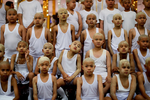 Boys with their heads smeared with thanaka bark wait to pray inside a temple after being shaved in preparation for an annual Poy Sang Long celebration, a traditional rite of passage for boys to be initiated as Buddhist novices, in Mae Hong Son, Thailand, April 2, 2018. (Photo by Jorge Silva/Reuters)