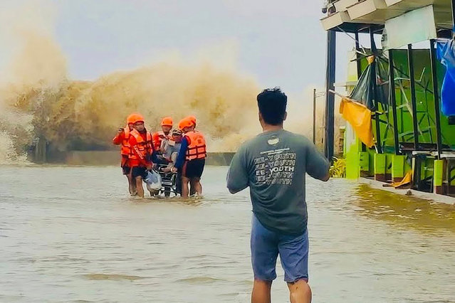 This handout photo taken on September 26, 2025 and released on September 27 by the Philippine Coast Guard shows coast guard personnel (background) evacuating a person at the height of Severe Tropical Storm Bualoi in San Agustin town, Romblon province. The Philippines evacuated hundreds of thousands of people and confirmed at least three deaths on Friday as it faced yet another tropical storm, days after it was battered by deadly Super Typhoon Ragasa. (Photo by Handout/Philippine Coast Guard (PCG)/AFP Photo)