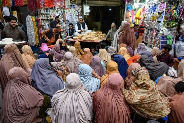 Burqa-clad women wait for free bread at a distribution point in Peshawar on April 3, 2023. Poor Pakistanis are feeling the brunt of the economic turmoil, and at least 20 people have been killed since the start of the Muslim fasting month of Ramadan in crowd crushes at food distribution centres. (Photo by Abdul Majeed/AFP Photo)