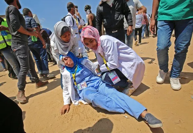 Palestinian woman medics tend to an injured colleague during clashes near the border with Israel, east of Khan Yunis in the southern Gaza Strip on May 15, 2018, amidst protests marking 70th anniversary of Nakba – also known as Day of the Catastrophe in 1948 – and against the US' relocation of its embassy from Tel Aviv to Jerusalem. (Photo by Said Khatib/AFP Photo)