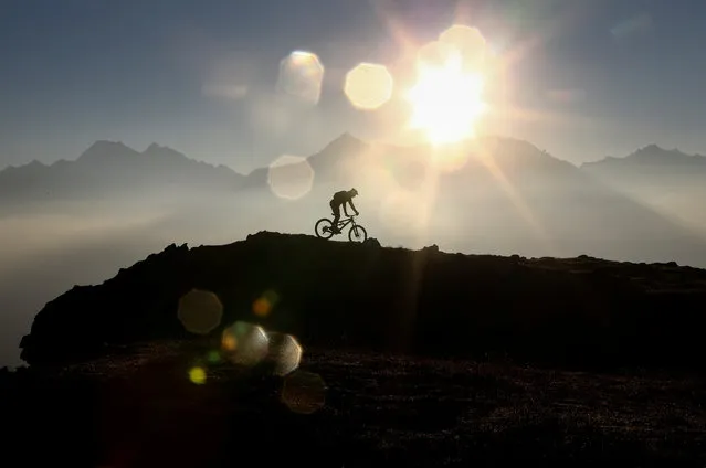 A man rides his mountian bike on a trail atop Eggerberg mountain as the sun rises in the western Austrian village of Noesslach, Austria September 30, 2016. (Photo by Dominic Ebenbichler/Reuters)