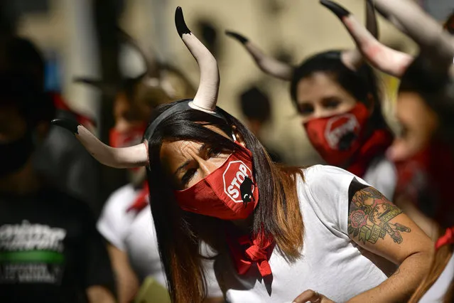 Demonstrators wear faces masks protection while protesting against San Fermin's bullfighting in front of the bull ring due canceled this year by the conoravirus, in Pamplona, northern Spain, Tuesday, July 7, 2020. (Photo by Alvaro Barrientos/AP Photo)