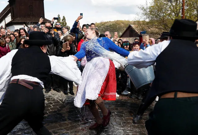 A woman dressed in traditional clothes reacts as men throw water at her during a traditional Easter celebration in Holloko, Hungary on April 18, 2022. (Photo by Bernadett Szabo/Reuters)