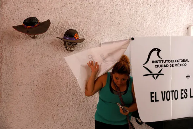 A woman emerges from a voting booth after filling out her ballot at a polling station during the presidential election in Mexico City, Mexico, July 1, 2018. (Photo by Carlos Jasso/Reuters)