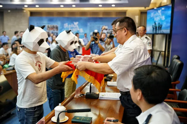 Whistleblowers wearing panda masks receive cash awards for reporting gang crimes from police officers at a news conference in Guangzhou, Guangdong province, China July 5, 2018. (Photo by Reuters/China Stringer Network)