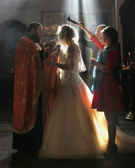 In this photo taken Saturday, January 31, 2015, a Georgian Orthodox clergyman blesses newly weds during a religious ceremony at an Orthodox cathedral in Tbilisi, Georgia. (Photo by Shakh Aivazov/AP Photo)