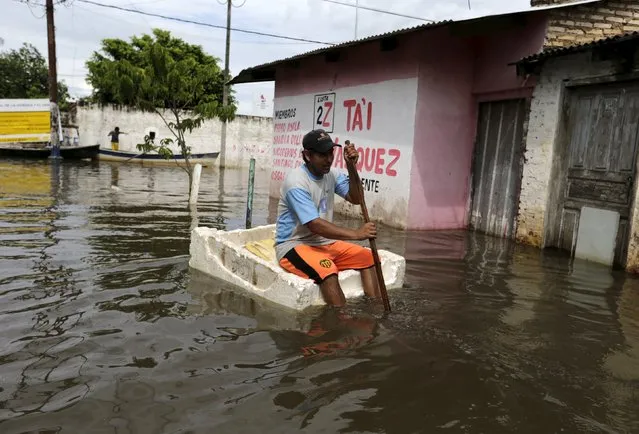 A man travels on a makeshift raft near flood-affected houses in Asuncion, December 27, 2015. (Photo by Jorge Adorno/Reuters)