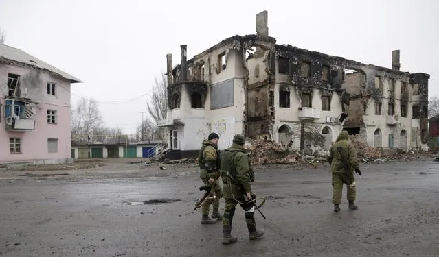A  pro-Russian rebels walk past a destroyed building in the town of Vuhlehirsk, Ukraine, Friday, February 6, 2015. (Photo by Petr David Josek/AP Photo)