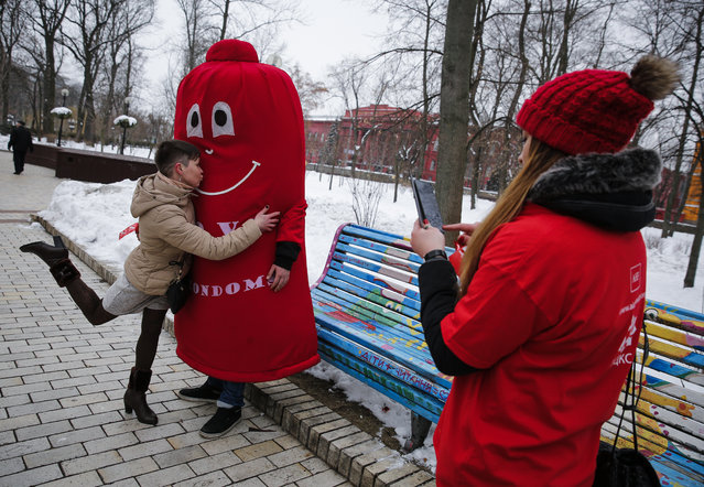 A volunteer photographs a woman as she kisses a volunteer wearing a condom costume during marking the International Condom Day in Kiev, Ukraine, 13 February 2015. The event was organized to promote and create awareness towards “Safe s*x” and the use of condoms to control and prevent Human Immunodeficiency Virus (HIV) and other sexually transmitted diseases on the occasion of the International Condom day. (Photo by Roman Pilipey/EPA)