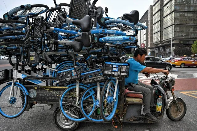 A man rides a tricycle loaded with bicycles on a street in Beijing on August 11, 2023. (Photo by Jade Gao/AFP Photo)