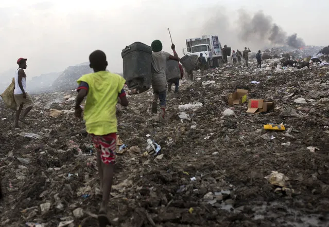 In this August 23, 2018 photo, trash scavengers run behind a truck before it dumps its load at the Truitier landfill in the Cite Soleil slum of Port-au-Prince, Haiti. Scavengers often suffer from chronic respiratory illnesses, headaches and infections contracted from used syringes. (Photo by Dieu Nalio Chery/AP Photo)