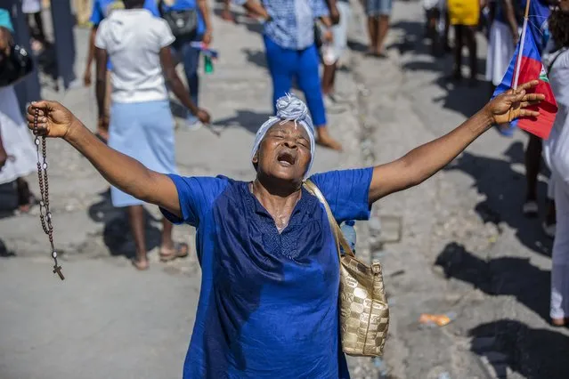 A woman holds out her arms as she prays during a religious march in Port-au-Prince, Haiti, Saturday, May 15, 2021. Hundreds of Haitians marched on the streets of Port-au-Prince after church services on Saturday to collectively pray outdoors for peace and an end to the wave of kidnappings that have victimized the city's residents. (Photo by Joseph Odelyn/AP Photo)
