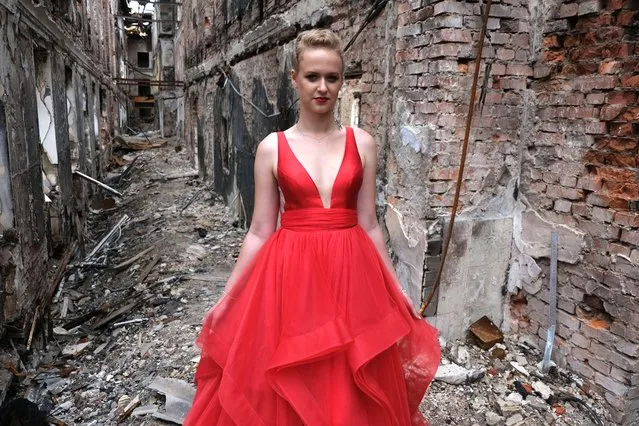 A student wearing her prom dress poses for a photo among the ruins of her school destroyed in a Russian shelling on February 27, in Kharkiv, Ukraine on June 7, 2022. Teenagers in their gowns which they would have worn for their prom organized a graduation ceremony in their destroyed school. (Photo by Abdullah Unver/Anadolu Agency via Getty Images)
