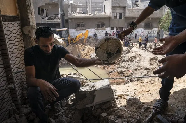A soccer ball is salvaged from the debris of the home of Nader al-Masri, a long-distance runner who participated in dozens of international competitions, including the 2008 Olympics, that was damaged when the home of Ramez al-Masri was destroyed by an air-strike prior to a cease-fire reached after an 11-day war between Gaza's Hamas rulers and Israel, Sunday, May 23, 2021, in Beit Hanoun, the northern Gaza Strip. (Photo by John Minchillo/AP Photo)
