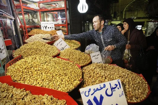 In this Thursday, February 2, 2012 file photo, an Iranian vendor sells pistachio in Tehran's old main bazaar. Iran has successfully transferred some of its formerly frozen assets in order to ensure that financial sanctions have been fully lifted in accordance with a historic nuclear deal, the head of the central bank said Tuesday, January 19. 2016. (Photo by Vahid Salemi/AP Photo)