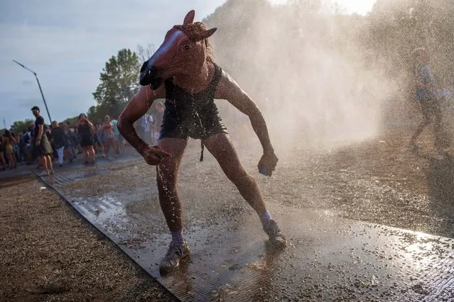 A festival goer cools himself with a mist machine, during the 28th Sziget (Island) Festival on Shipyard Island, Northern Budapest, Hungary, 13 August 2022. The festival is one of the biggest cultural events of Europe offering art exhibitions, theatrical and circus performances and above all music concerts. (Photo by Marton Monus/EPA/EFE)