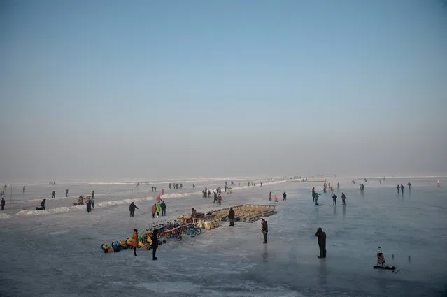 People gather on a frozen riverbank in Harbin on January 5, 2017. (Photo by Nicolas Asfouri/AFP Photo)