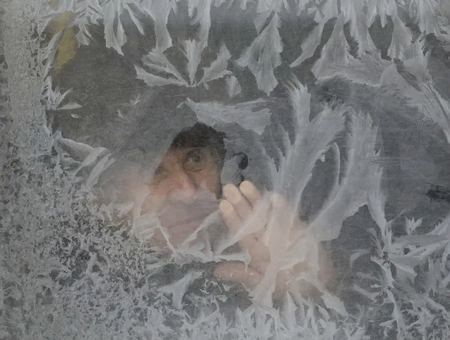 A man looks through a frosted bus window with the air temperature at about minus 16 degrees Celsius (3.2 degrees Fahrenheit), in Lviv, Ukraine January 6, 2017. (Photo by Gleb Garanich/Reuters)
