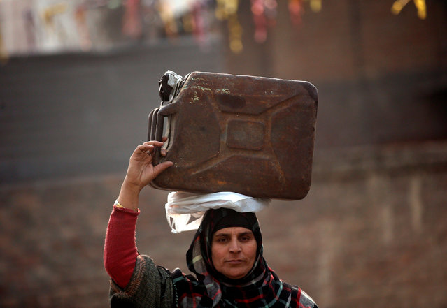 A woman carries a jerrycan filled with kerosene oil for cooking on the outskirts of Srinagar, December 28, 2016. (Photo by Danish Ismail/Reuters)
