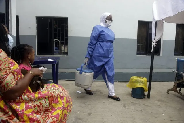 A nurse carries a box containing Moderna vaccines at the health center in Lagos, Nigeria Wednesday, August 25, 2021. Nigeria has begun the second rollout of COVID-19 vaccines as it aims to protect its population of more than 200 million amid an infection surge in a third wave of the pandemic. (Photo by Sunday Alamba/AP Photo)