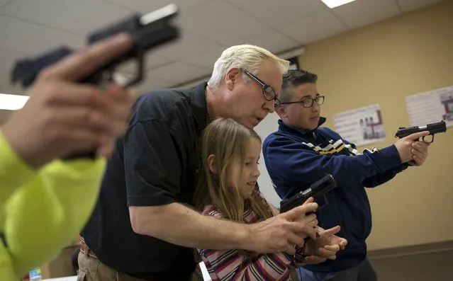 Instructor Jerry Kau shows student Joanna Zuber how to hold a handgun alongside Sam Minnifield (L-R) during a Youth Handgun Safety Class at GAT Guns in East Dundee, Illinois, April 21, 2015. (Photo by Jim Young/Reuters)