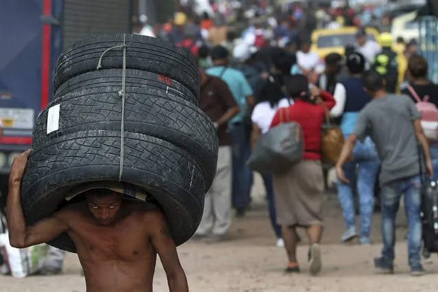A man carries a set of used tires into Venezuela, through a blind spot on the border near the Simon Bolivar International Bridge in La Parada, Colombia, Thursday, February 28, 2019. The tires were bought in Cucuta, Colombia and carried across the border into Venezuela. (Photo by Martin Mejia/AP Photo)