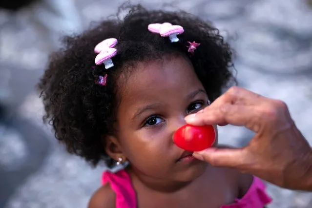 A clown nose is placed on a child's face during a protest opposing violence against women after the murder of Venezuelan actress and clown Julieta Inés Hernández Martínez in Rio de Janeiro, Brazil, Monday, January 8, 2024. The body of Hern·ndez, who had been missing since Dec. 23 while traveling by bicycle, was found in Presidente Figueiredo city, near Manaus in Amazonas state. (Photo by Bruna Prado/AP Photo)