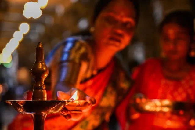 A devotee lights an oil lamp while offering prayers during the celebrations to mark Diwali, the Hindu festival of lights, at a temple in Colombo on November 12, 2023. (Photo by Ishara S. Kodikara/AFP Photo)