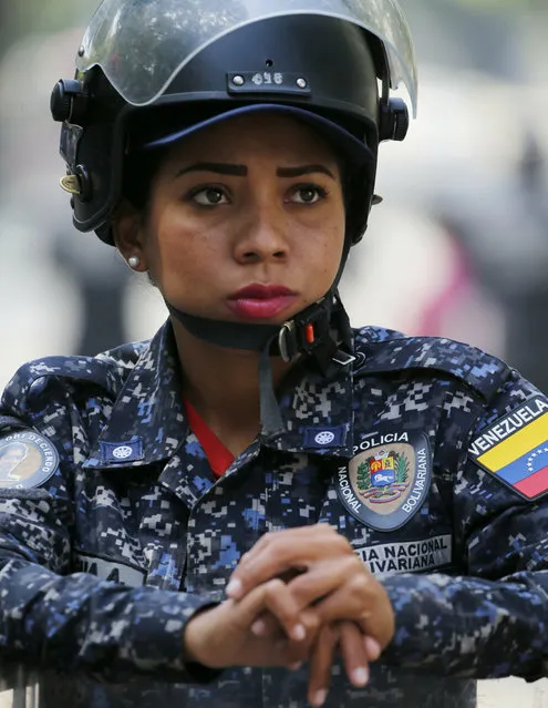A police stands guard in anticipation of a march called by a coalition of opposition parties and civic groups who are petitioning lawmakers for a law of guarantees that will protect workers who have been victims of political retaliation and unjustified dismissals, in Caracas, Venezuela, Tuesday, March 19, 2019. (Photo by Fernando Llano/AP Photo)