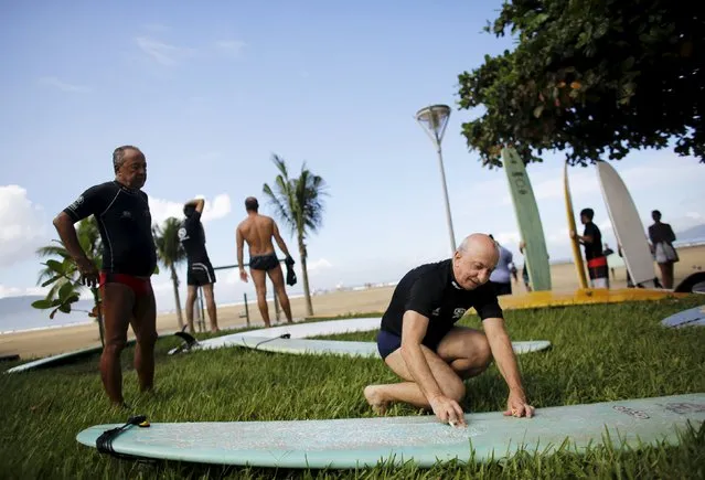 Claudines Garcia (R), 64, puts paraffin wax on a surfboard to avoid slipping as Wagner Barbosa, 67, stands by before their surf class in Santos, Sao Paulo state, Brazil March 17, 2016. (Photo by Nacho Doce/Reuters)