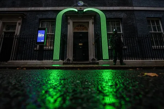 A green arch is lit over the door of number 10 Downing Street in London on October 29, 2021 in preparation for the COP26 summit which will be taking place in Glasgow. (Photo by Chris J. Ratcliffe/AFP Photo)