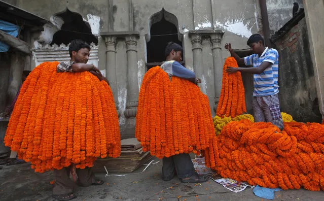 Labourers unload garlands of marigold flowers to sell at a wholesale flower market ahead of the Durga Puja festival in Kolkata October 19, 2012. (Photo by Rupak De Chowdhuri/Reuters)