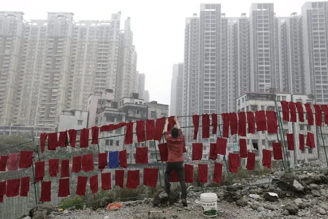 A man hangs towels on fences in an abandoned village near buildings of a residential compound in Guangzhou, Guangdong Province, China, March 18, 2016. (Photo by David Johnson/Reuters)