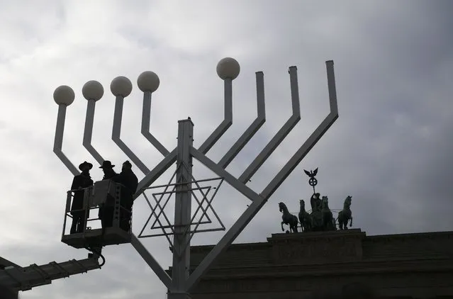 Rabbi Yehuda Teichtal, second from left, and Rabbi Segal Shmoel, left, inspect a giant Hanukkah Menorah, set up by the Jewish Chabad Educational Center ahead of the Jewish Hanukkah holiday, at the Pariser Platz in Berlin, Germany, Friday, November 26, 2021. (Photo by Markus Schreiber/AP Photo)