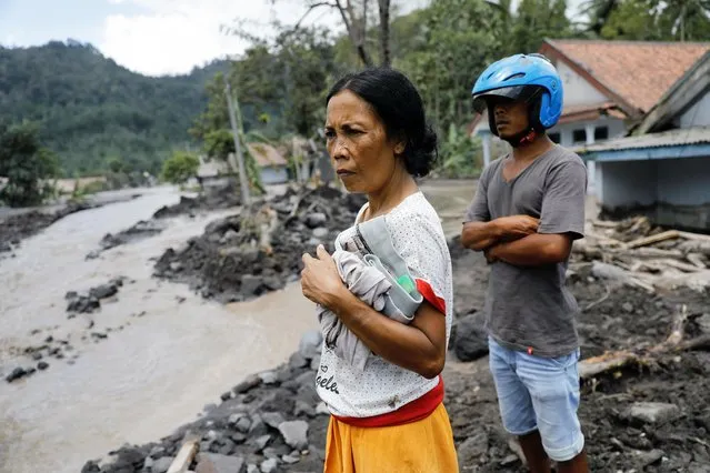 Rusmini, 47, and his son Untung Susanto, 30, look around as they try to visit their house that submerged with lava after the eruption of Mount Semeru volcano, in Kamar Kajang, Candipuro district, Lumajang, East Java province, Indonesia, December 9, 2021. (Photo by Willy Kurniawan/Reuters)