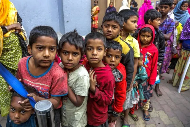 Homeless children stand in a queue to receive morning meal from Missionaries of Charity, the order founded by Saint Teresa, at its headquarter in Kolkata, India, Tuesday, December 28, 2021. India‚ government has blocked Mother Teresa, charity from receiving foreign funds, saying the Catholic organization did not meet conditions under local laws, dealing a blow to one of the most prominent groups running shelters for the poor. (Photo by Bikas Das/AP Photo)