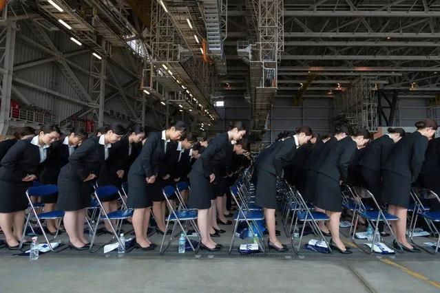 Newly-hired employees bow as they attend the entrance ceremony for ANA Group in an airplane hangar at Haneda Airport on April 01, 2024 in Tokyo, Japan. 2848 new employees from 37 group companies attended the ceremony, held by the country's largest air carrier group of companies, as Japan's fiscal year starts from April 1. (Photo by Tomohiro Ohsumi/Getty Images)
