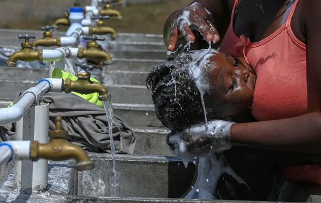 A migrant bathes his child at the San Vicente Migrants Reception Station (SRM) in Meteti, Darien Province, in Panama on February 9, 2021. Migrants from Haiti and several African countries are stranded at the Panama-Colombia border, while the Central American country is expecting a new wave of migrants. (Photo by Luis Acosta/AFP Photo)