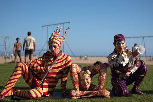 Cirque du Soleil performer Mitch Wynter, known as the, Trickster, left, is joined by contortionist Sender Enkhtur, center, and Wei-Liang Lin at Santa Monica Beach as they pose for photos, Monday, April 29, 2024, in Santa Monica, Calif. Cirque du Soleil announced their return to the Santa Monica Pier this fall after being gone for over a decade. (Photo by Richard Vogel/AP Photo)