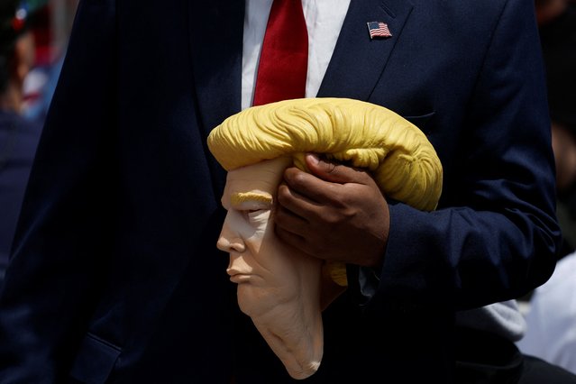 A man holds a mask depicting former U.S. President and Republican presidential candidate Donald Trump on the day of his campaign rally in Wildwood, New Jersey, U.S., May 11, 2024. (Photo by Evelyn Hockstein/Reuters)