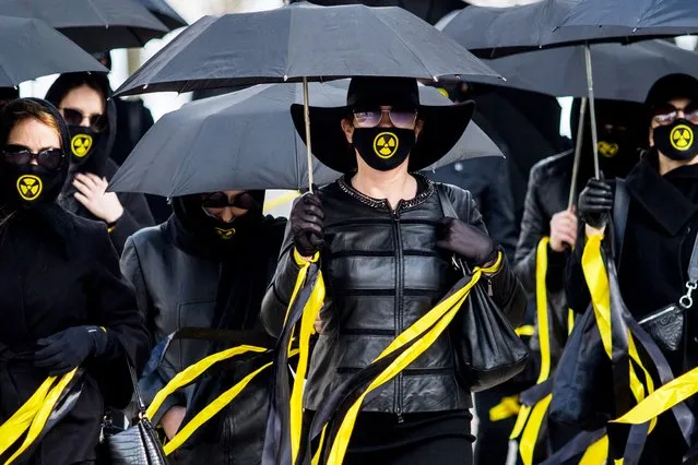 Women wearing black clothing and face masks with radioactivity sign march under umbrellas in Minsk, on April 26, 2021, to commemorate the victims of the Chernobyl nuclear disaster on the 35th anniversary of the tragedy. (Photo by AFP Photo/Stringer)