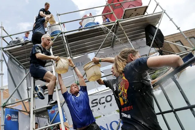 Members of a Belgian team from Antwerp pass 30-pound (13.6 kg) bags of water up the ladder in the bucket brigade competition of the Firefighter Muster event at the World Fire and Police Games in Fairfax, Virginia July 4, 2015. (Photo by Jonathan Ernst/Reuters)