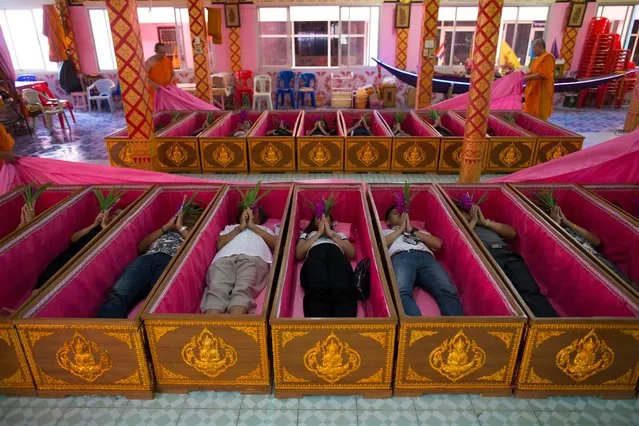 Thai devotees lie inside coffins as Buddhist monks officiate during a coffin ritual at Wat Takien temple in Nonthaburi province, Thailand, 01 April 2017 (issued 02 April 2017). The Buddhist temple offers believers to attend the resurrection ritual by laying down in coffins while monks pass a cloth over them, chant a dirge for the symbolic death and then rise up again believing that they are cleansed of their karma, get rid of bad luck and reborn for a fresh start in life with protection from harm, wealthy, good health and their wishes completely fulfilled. (Photo by Rungroj Yongrit/EPA)